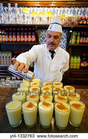 Stock Image - Barman putting Cinnamon on drinks of? Boza? The Vefa Bozacisi Shop, Istanbul, Turkey. Fotosearch