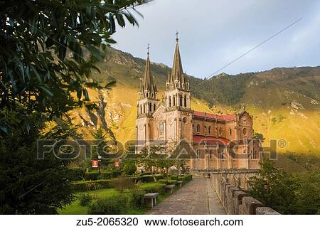 Stock Image - Basilica of Santa Maria la Real de Covadonga. Conceived by Robert Frassinelli and built between 1877 and 1901 by architect Frederick Aparicio and Soriano, Romanesque Revival style built entirely of pink limestone.. Fotosearch