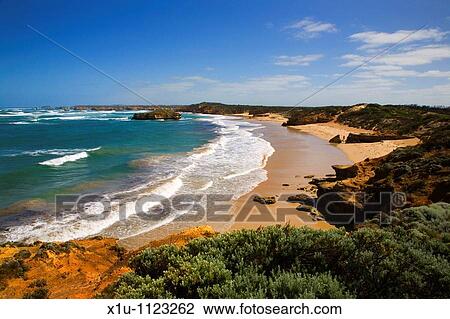 Stock Image - Bay of Martyrs with person standing between rocks on the beach Great Ocean Road Victoria Australia. Fotosearch