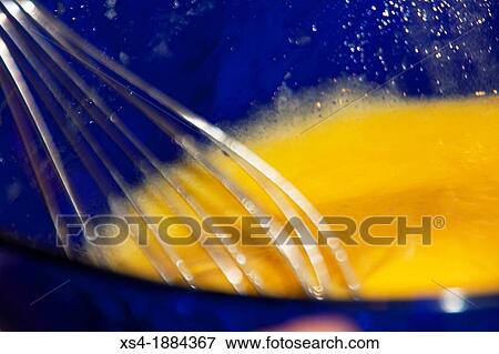 Stock Photo - Beating eggs Beating 6 eggs using a whisk in a blue glass bowl The eggs should be beated vigorously to add air on the mixture The well beaten egg can be used in baking, batter omelet or something. Fotosearch