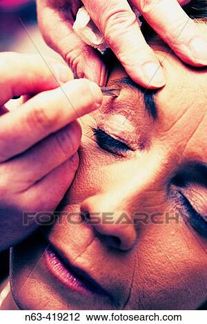 Beautician plucking eyebrow of a middle aged woman View Large Photo Image Stock Image - Beautician plucking eyebrow of a middle aged woman. Fotosearch