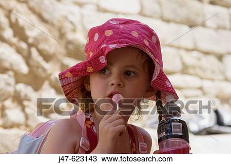 Beautiful 5 year old girl wearing a sunhat, with pigtails, looking off camera sucking a lolly. View Large Photo Image Stock Image - Beautiful 5 year old girl wearing a sunhat, with pigtails, looking off camera sucking a lolly.. Fotosearch