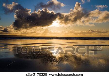 Beautiful beach sunset reflected in the standing water at low tide. Westward Ho!, North Devon, England. View Large Photo Image Stock Photo - Beautiful beach sunset reflected in the standing water at low tide. Westward Ho!, North Devon, England.. Fotosearch
