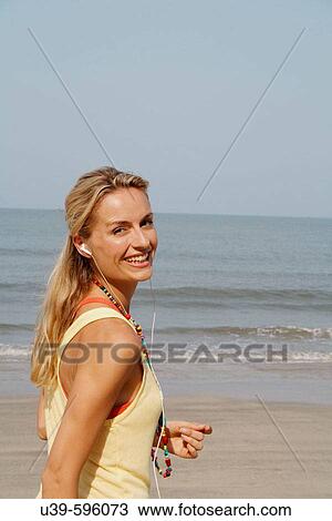 Beautiful blonde woman wearing headphones and smiling on a beach in India. View Large Photo Image Stock Image - Beautiful blonde woman wearing headphones and smiling on a beach in India.. Fotosearch
