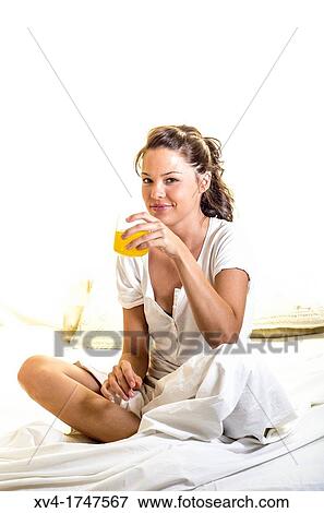 Stock Photo - Beautiful girl take a breakfast with orange juice on the bed in the morning. Fotosearch