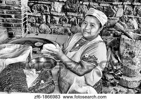 Stock Image - Beautiful local woman making tortillas at over in La Posada de Don Rodrigo restaurant in Antigua Guatemala. Fotosearch