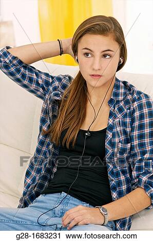 Beautiful teenage girl listen to music with headphones, and sitting on a sofa at home View Large Photo Image Stock Image - Beautiful teenage girl listen to music with headphones, and sitting on a sofa at home. Fotosearch