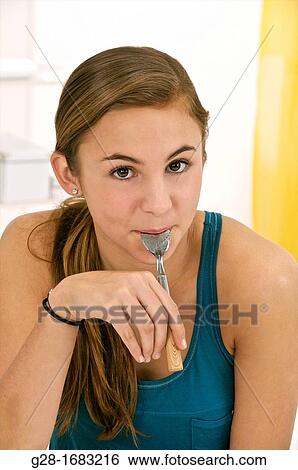Stock Photograph - Beautiful teenage girl with a teaspoon in her mouth. Fotosearch