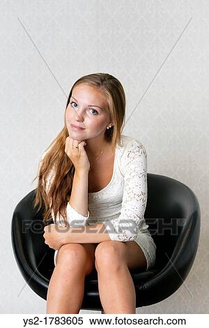 Beautiful young adult female sits in vintage chair looking pensive View Large Photo Image Stock Photography - Beautiful young adult female sits in vintage chair looking pensive. Fotosearch