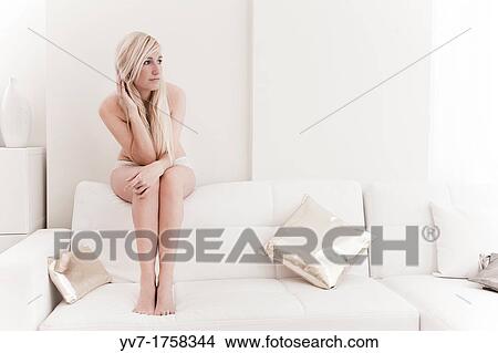 Beautiful young blonde sitting on the couch and looking out the window View Large Photo Image Picture - Beautiful young blonde sitting on the couch and looking out the window. Fotosearch