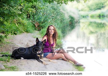 Stock Photograph - Beautiful young caucasian woman with her German Shepherd dog by Latah Creek in Spokane, Washington, USA. Fotosearch