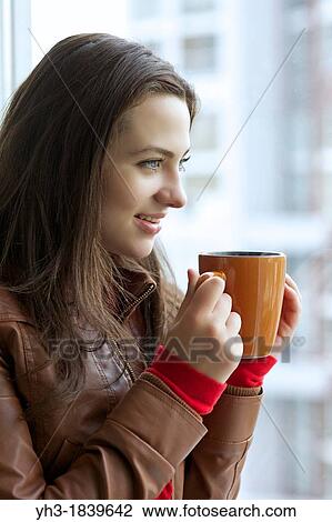Beautiful young girl drinking hot tea while looking at the window View Large Photo Image Stock Image - Beautiful young girl drinking hot tea while looking at the window. Fotosearch