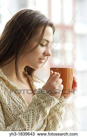 Beautiful young girl drinking hot tea while looking at the window View Large Photo Image Stock Image - Beautiful young girl drinking hot tea while looking at the window. Fotosearch