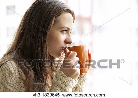 Beautiful young girl drinking hot tea while looking at the window View Large Photo Image Stock Photography - Beautiful young girl drinking hot tea while looking at the window. Fotosearch