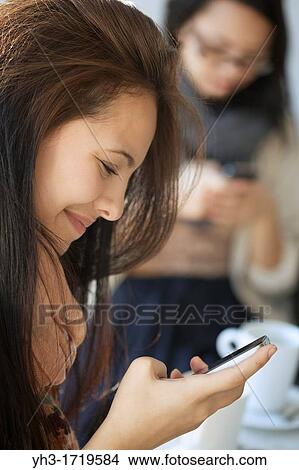 Beautiful young girl holding a smartphone View Large Photo Image Picture - Beautiful young girl holding a smartphone. Fotosearch