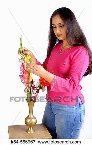 Stock Photo - Beautiful, young lady in pink top and jeans making flower arrangements.. Fotosearch