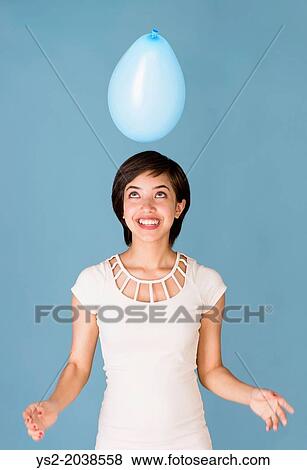 Beautiful young multiracial woman having fun with blue balloon at celebration. View Large Photo Image Stock Photo - Beautiful young multiracial woman having fun with blue balloon at celebration.. Fotosearch