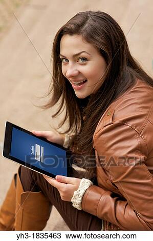 Beautiful young woman checking her Facebook newsfeed on an iPad View Large Photo Image Stock Image - Beautiful young woman checking her Facebook newsfeed on an iPad. Fotosearch