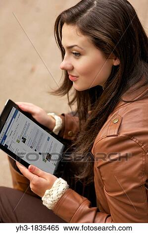 Beautiful young woman checking her Facebook newsfeed on an iPad View Large Photo Image Stock Photography - Beautiful young woman checking her Facebook newsfeed on an iPad. Fotosearch