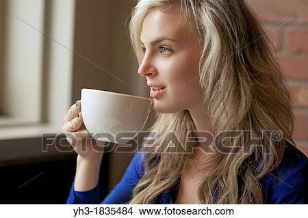 Beautiful young woman drinking coffee at a cafe View Large Photo Image Picture - Beautiful young woman drinking coffee at a cafe. Fotosearch