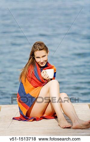 Stock Photo - Beautiful young woman enjoying a coffee in a dock by the sea. Fotosearch