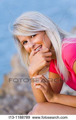 Stock Photo - Beautiful young woman is biting her finger. Fotosearch