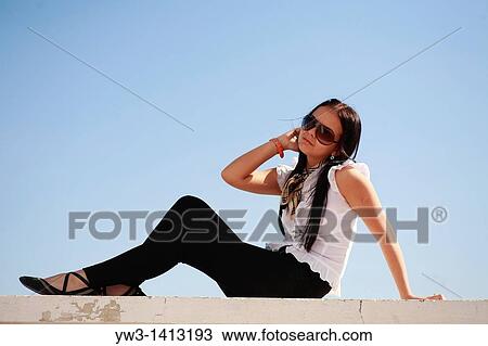 Stock Image - Beautiful young woman posing against sky Summer photo. Fotosearch