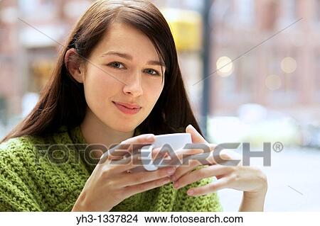 Picture - Beautiful young woman relaxing with her cappuccino outdoor. Fotosearch