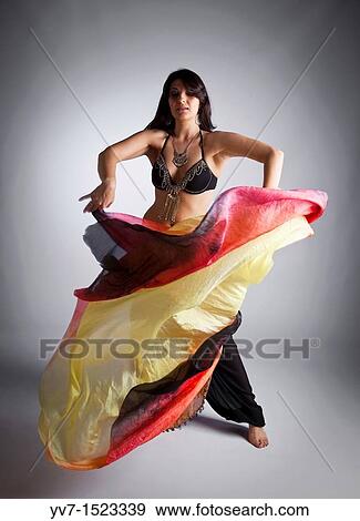 Stock Photo - Beautifull belly dancer with veil over white background. Fotosearch