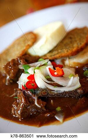 Stock Image - Beef Goulash with bread dumplings and potatoes pancakes, a traditional Czech dish Prague, Czech Republic. Fotosearch