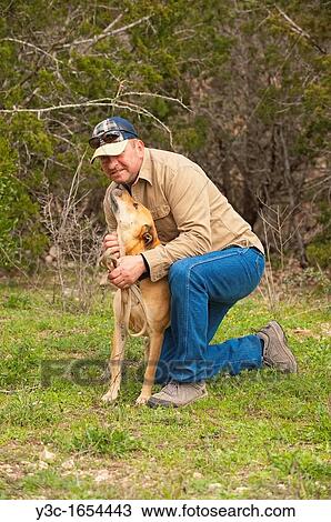 Stock Image - Beige colored dog reaching trying to lick the face of middle-aged man. Fotosearch