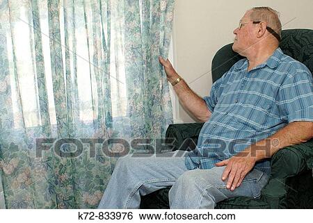 Stock Photograph - Being elderly can sometimes restrict the person's abilities causing them to stay at home and just look from inside to the outer world. Fotosearch