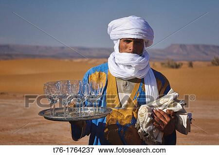 Stock Photo - Berber serving wine at a luxury camp in the Sahara Desert at Erg Chigaga, Morocco. Fotosearch