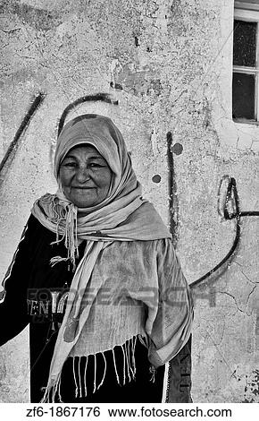 Stock Photograph - Berber woman in front of her old ancient Berber village in Ksar in Metameur near Djerba Tunisia Africa. Fotosearch