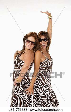 Stock Image - Best friends in their early 40s wearing exactly the same dress. Fotosearch