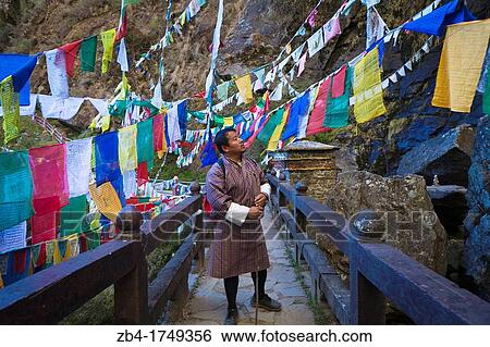 Stock Photograph - Bhutanese man crossing the bridge to the Taktsang Monastery Tiger's Nest, Paro Valley, Bhutan, Asia.. Fotosearch