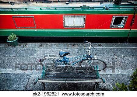 Stock Image - Bike and boat parked next to a bench, Regents canal, London, UK. Fotosearch