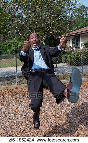 Black african american man in 40s dressed in business suit having so much fun on swing in park with no business stress View Large Photo Image Picture - Black african american man in 40s dressed in business suit having so much fun on swing in park with no business stress. Fotosearch