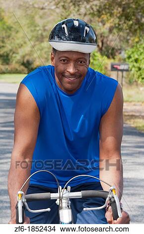 Black african american man in 40s dressed in sports wear on bike exercising in park with no business stress View Large Photo Image Picture - Black african american man in 40s dressed in sports wear on bike exercising in park with no business stress. Fotosearch