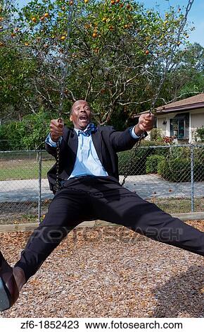 Black african american man in 40s dressed in business suit having so much fun on swing in park with no business stress View Large Photo Image Stock Image - Black african american man in 40s dressed in business suit having so much fun on swing in park with no business stress. Fotosearch