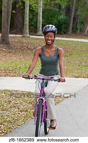 Black African girl aged 18 riding bike with helmet in neighborhood for exercise View Large Photo Image Stock Photo - Black African girl aged 18 riding bike with helmet in neighborhood for exercise. Fotosearch
