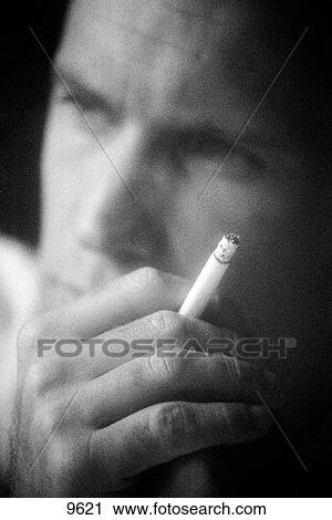 Stock Image - Black and white close up photograph of man holding cigarette. Fotosearch