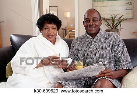 Black couple in robes reading the newspaper View Large Photo Image Stock Photo - Black couple in robes reading the newspaper. Fotosearch
