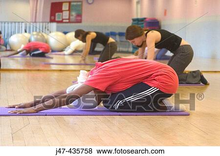 Black lady stretching on floor in a pilates class View Large Photo Image Stock Photo - Black lady stretching on floor in a pilates class. Fotosearch