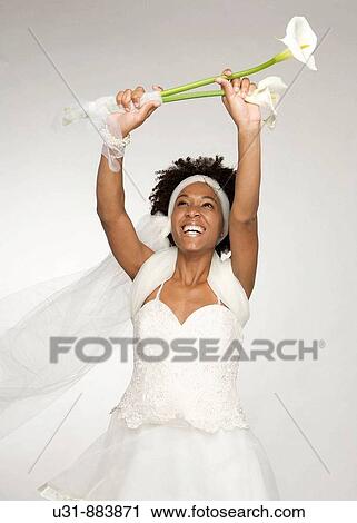 Stock Image - Black Latin Bride with wavy hair plays with a bouquet. Fotosearch