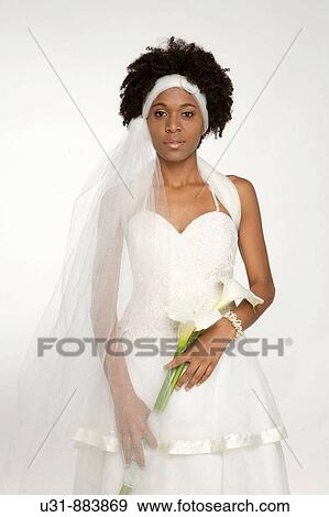 Stock Photo - Black Latin Bride with wavy hair plays with a bouquet. Fotosearch