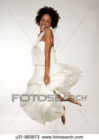 Stock Image - Black Latin girl bride with sexy wavy hair jumps. Fotosearch