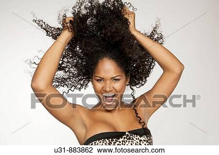 Stock Image - Black Latin girl pulls her sexy wavy hair. Fotosearch