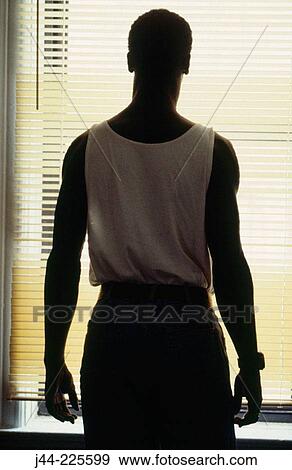 Black man standing by blinds in the room View Large Photo Image Stock Photo - Black man standing by blinds in the room. Fotosearch