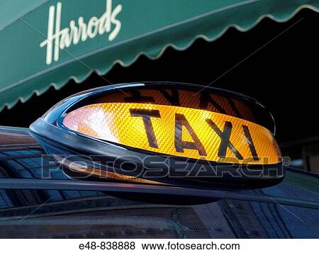 Stock Photo - BLACK TAXI FOR HIRE SIGN HARRODS DEPARTMENT STORE KNIGHTSBRIDGE LONDON ENGLAND UK. Fotosearch